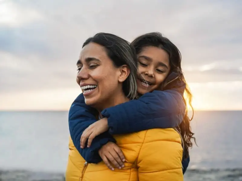 Cape Breton Winter: A young grandmother smiles as she gives her granddaughter a piggy-back ride along a Cape Breton Island shore.