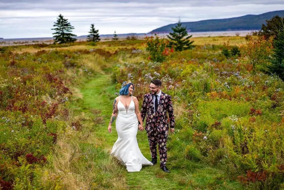 Cape Breton Wedding: A newlywed couple smiles while walking along a trail at Cabot Shores.