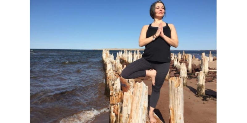 Woman doing a yoga pose on a shore with wood posts