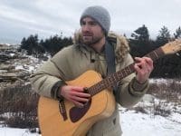 George Woodhouse playing guitar outdoors in the winter