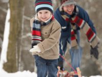 A young boy playfully runs away from his father during a winter getaway in Nova Scotia.