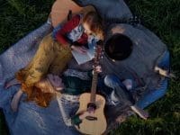 Hearts of Kin band membes laying on a blanket on grass with guitars