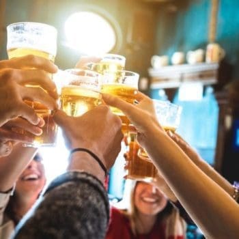 A group of friends clang their glasses in celebration of breweries in Cape Breton.
