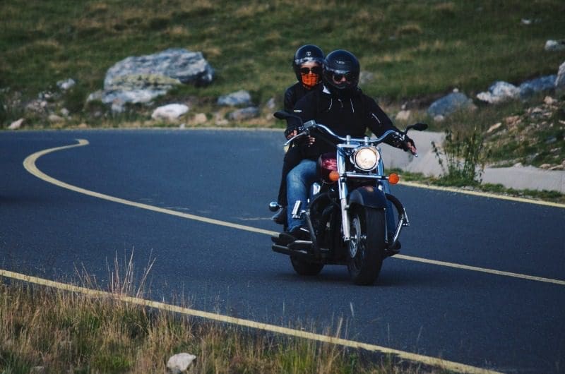 A couple rides along the road during a Cabot Trail motorcycle tour.
